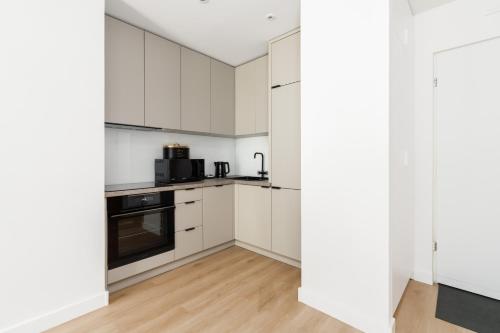 a white kitchen with white cabinets and appliances at Cozy Black & White Studio in City Center with FREE GARAGE Poznań by Renters in Poznań