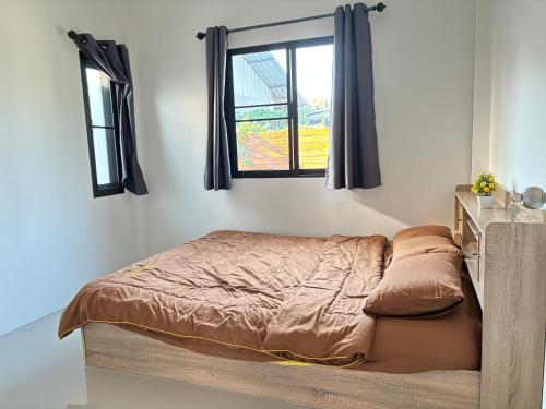 Bett in einem Schlafzimmer mit Fenster in der Unterkunft บ้านม่วนใจ๋สันกำแพง in San Kamphaeng