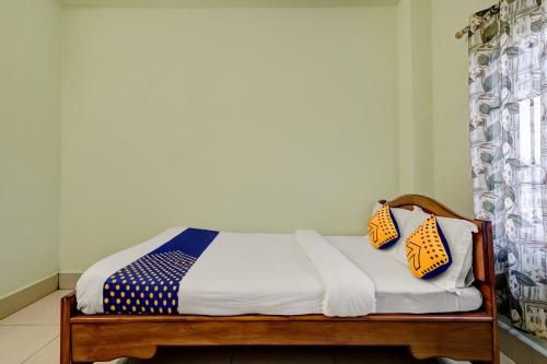 un letto con due cuscini sopra in una stanza di SPOT ON Sunrise Lodge & Axomiya Dhaba a Kāhārpāra