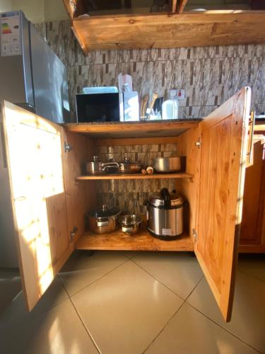 a kitchen with wooden cabinets with pots and pans at E&E Holiday Apartment in Dar es Salaam