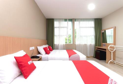 a hotel room with two beds with red pillows at Capital O 89344 Labuan Avenue Hotel in Labuan