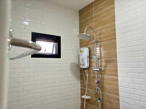 a bathroom with a shower with a tv on the wall at บ้านม่วนใจ๋สันกำแพง in San Kamphaeng