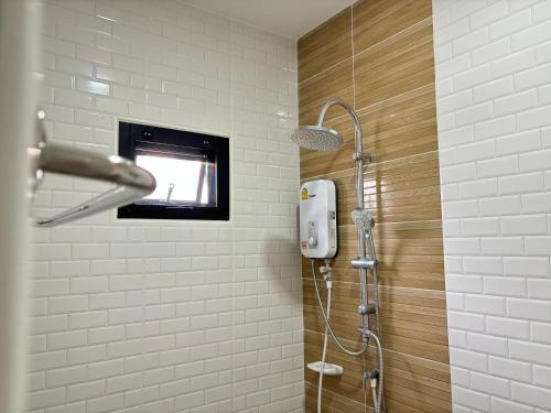 ein Bad mit einer Dusche und einem TV an der Wand in der Unterkunft บ้านม่วนใจ๋สันกำแพง in San Kamphaeng