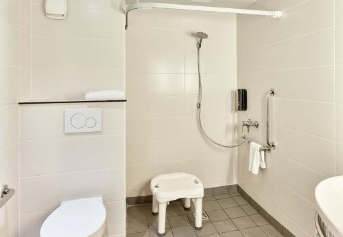 uma casa de banho com um chuveiro, um WC e um banco em B&B HOTEL Paris Italie Porte de Choisy em Ivry-sur-Seine