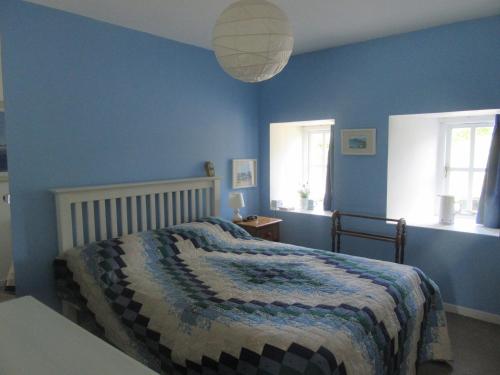 a bedroom with blue walls and a bed with a blanket at The Steps Llandeloy in Llandeloy