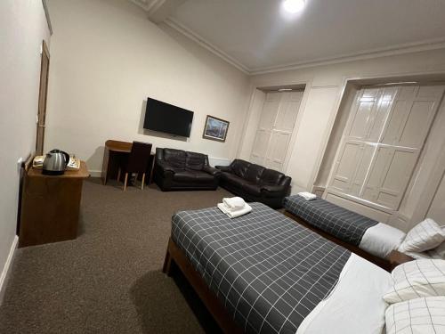 Habitación con 2 camas, sofá y TV. en Burntisland House, en Burntisland