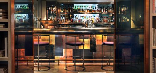 a bar with stools in front of a bar at The Hari London in London
