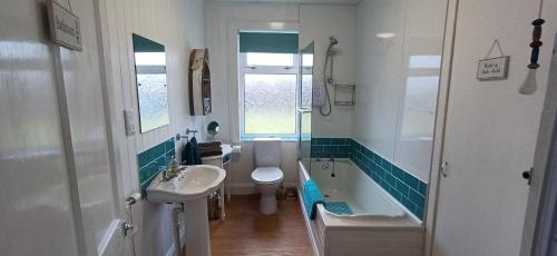 a bathroom with a tub and a sink and a toilet at Seascape Cottage in Knock