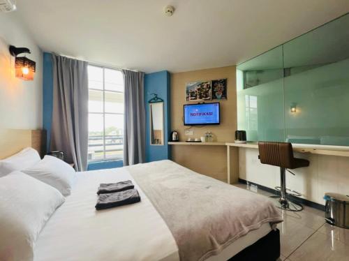 a bedroom with a bed and a desk and a television at Dolphin Hotel in Klang