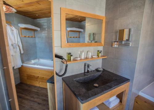 a bathroom with a sink and a tub at Hôtel L'Atelier de Donat in Malbuisson