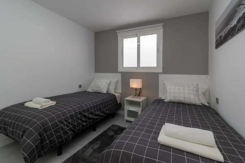 a bedroom with two beds and a window at Bungalow con piscina comunitaria in Chayofa