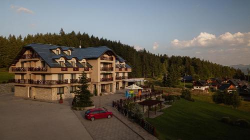 a large house with a red car parked in front of it at Hotel Green in Dolný Kubín