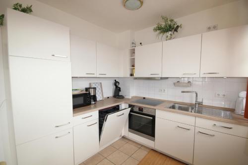 una cocina blanca con armarios blancos y fregadero en Atlantic 29, en Grömitz