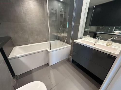 a bathroom with a tub and a sink and a toilet at Modern 2-bed Apartment 5 mins from London Bridge in London