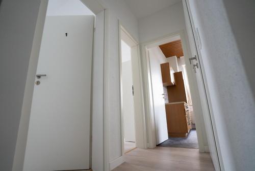 a hallway with two white doors and a hallway with a kitchen at Mieterlux Frankfurt Obertshausen in Obertshausen