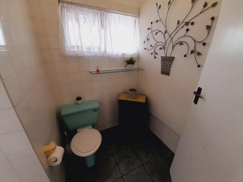a small bathroom with a green toilet and a window at Sea Breeze Shelly Beach in Shelly Beach