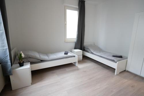 two white beds in a room with a window at Mieterlux Frankfurt Obertshausen in Obertshausen