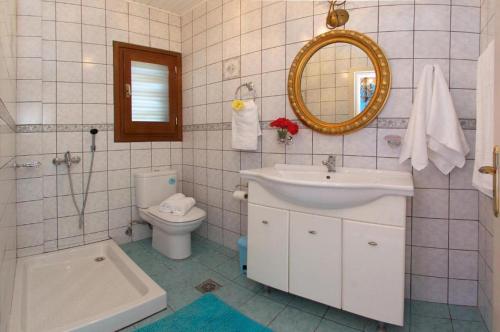bagno con lavandino, servizi igienici e specchio di Villa Nikos a Karavádhos
