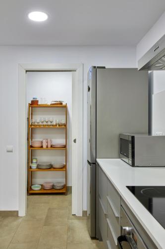 a kitchen with a refrigerator and a shelf with dishes at La Caseta del Fai in Riells del Fay