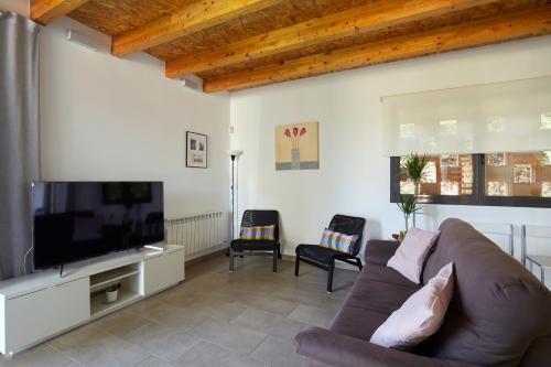 a living room with a couch and a flat screen tv at La Caseta del Fai in Riells del Fay