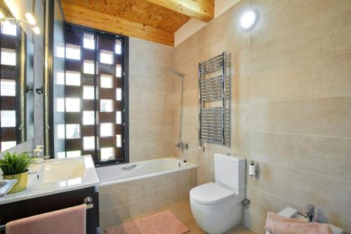 a bathroom with a toilet and a tub and a sink at La Caseta del Fai in Riells del Fay