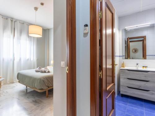 a bedroom with a bed and a bathroom with a sink at Lux Bormujos - Vacacional Sevilla in Bormujos