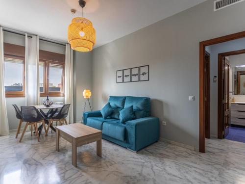 a living room with a blue couch and a table at Lux Bormujos - Vacacional Sevilla in Bormujos