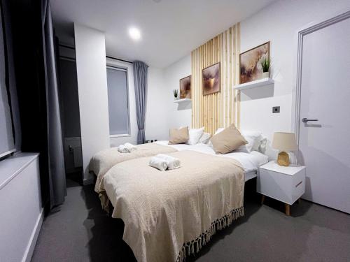 Impeccable 2-Bed Luxury Apartment in Berkshire في براكنيل: غرفة نوم بسريرين يوجد مناشف على السرير