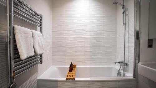 Impeccable 2-Bed Luxury Apartment in Berkshire في براكنيل: حمام أبيض مع حوض استحمام ودش