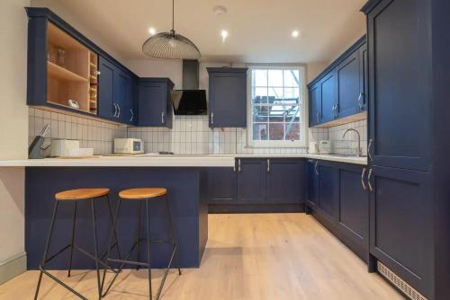 a kitchen with blue cabinets and two bar stools at Stylish Grade II listed house - Pass the Keys in Cheltenham