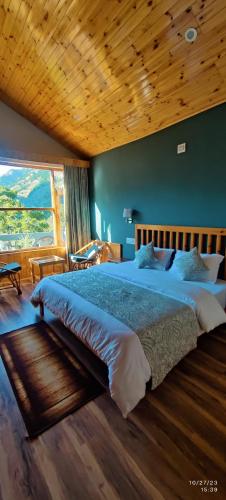 a bedroom with a large bed with a wooden ceiling at Doris Mountain Cabins Tirthan in Banjār