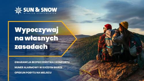 a man and woman sitting on a rock overlooking the ocean at Apartamenty Sun & Snow Park Sportowy in Krynica Zdrój