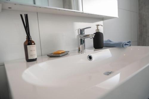 un lavandino bianco nel bagno con una bottiglia di vino e una bottiglia di Panorama view! Modern,Balcony/parking a Bodø