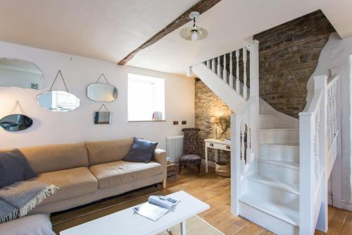 a living room with a couch and a staircase at Quay Cottage Llandeilo in Llandeilo