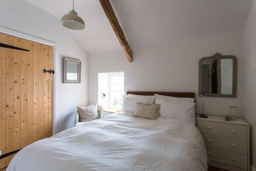 a bedroom with a white bed with a dresser and a mirror at Quay Cottage Llandeilo in Llandeilo