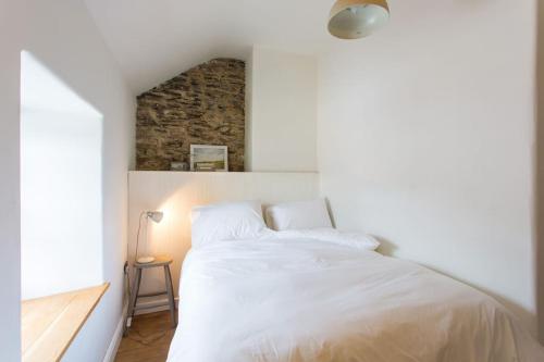 a bedroom with a white bed and a brick wall at Quay Cottage Llandeilo in Llandeilo