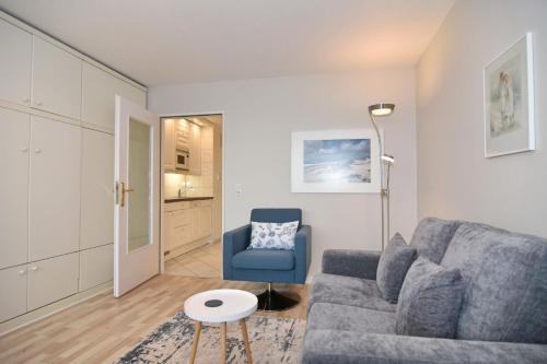 un salon avec un canapé gris et un fauteuil bleu dans l'établissement Metropol, Whg 92, Landseite, à Westerland