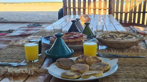 a picnic table with a plate of donuts and orange juice at Secret Spot Dakhla in Dakhla