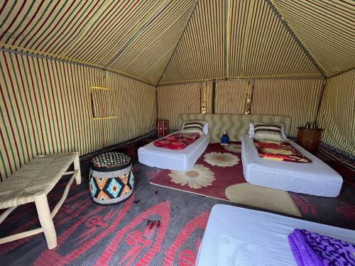 a room with two beds and a bench in a yurt at Secret Spot Dakhla in Dakhla