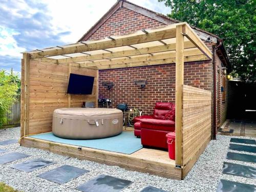 a wooden shed with a chair and a ottoman at 1 Bedroom home with hot tub & private garden in Orpington