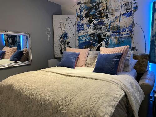 1 dormitorio con 1 cama grande con almohadas azules en 1 Bedroom home with hot tub & private garden en Orpington