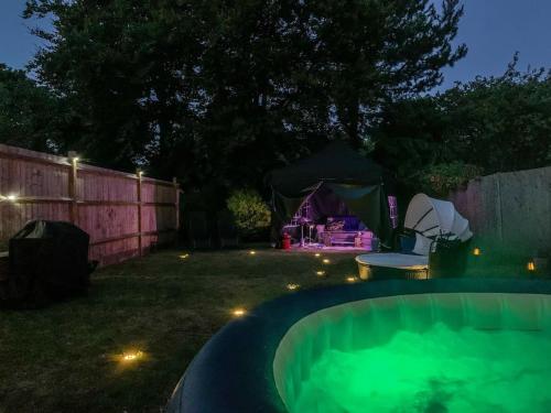 un cortile posteriore notturno con vasca idromassaggio e tenda di 1 Bedroom home with hot tub & private garden a Orpington