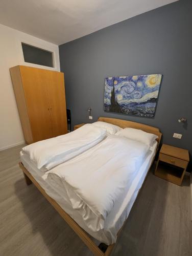 a bed in a bedroom with a painting on the wall at Casa Marica - Appartamento nel Borgo di Pieve in Tremosine Sul Garda