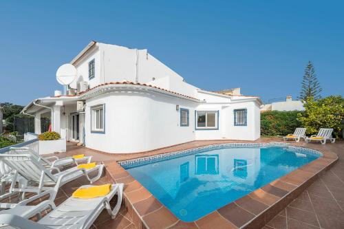 a villa with a swimming pool in front of a house at Casa Alegria Carvoeiro in Carvoeiro