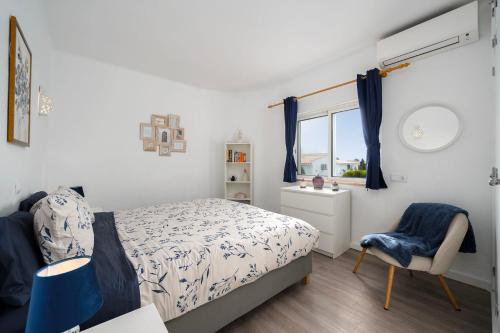 a bedroom with a bed and a chair and a window at Casa Alegria Carvoeiro in Carvoeiro