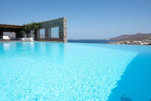 a pool of blue water with a house in the background at Villa Victoria with Sea View and Two Private Pools in Elia