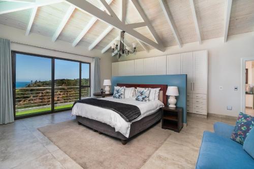 a bedroom with a bed and a view of the ocean at Super Beachfront views- Executive Villa - 6 bedrooms in Knysna