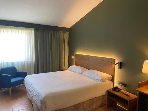 een hotelkamer met een bed en een blauwe stoel bij El Vilar de la Duquessa By Duquessa Hotel Collection in Cardona