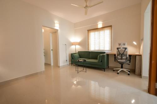 a living room with a green couch and a chair at HomeSlice Whitefield - 1BHK/ 2BHK Apartment/ Studio Room in Bangalore
