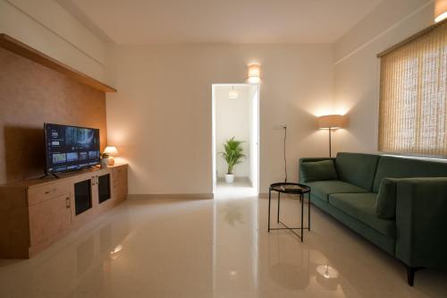 a living room with a green couch and a television at HomeSlice Whitefield - 1BHK/ 2BHK Apartment/ Studio Room in Bangalore